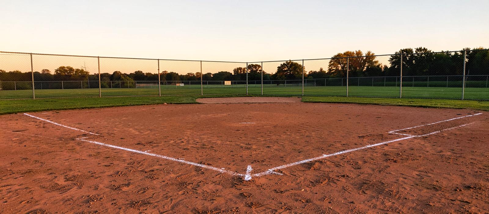Empty youth baseball diamond at sunset with freshly chalked lines